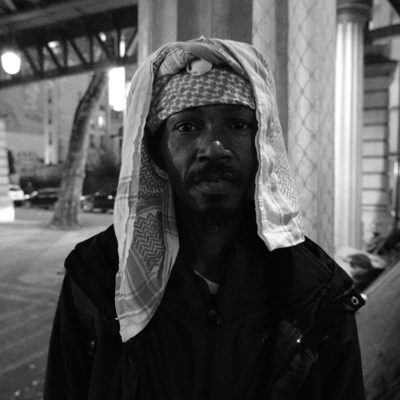 Man with a scarf over his head under the elevated metro